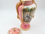 a pink vase with a picture on it next to a box
