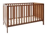 Le lit de bébé est en bois et est équipé d'un matelas blanc.