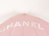 pink umbrella with chanel written on it sitting on top of a table