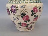 a white vase with pink flowers on it on a table