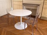 une table et des chaises blanches dans une pièce au sol en parquet