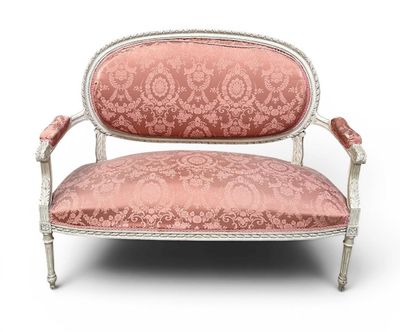 une chaise rose et blanche aux accoudoirs rembourrés et ouvragés