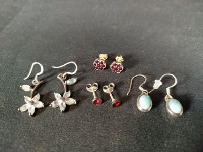 quatre paires de boucles d'oreilles sont posées sur une surface noire