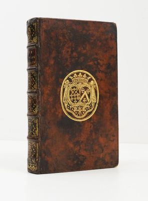un vieux livre orné d'un emblème doré posé sur une surface blanche