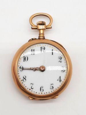 gros plan d'une montre de poche en or sur une surface blanche