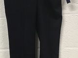 black pants hanging on a hanger against a white brick wall