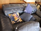 a black leather couch with pillows on it in a living room