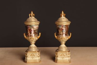 une paire de vases anciens posés sur une table, sur fond noir
