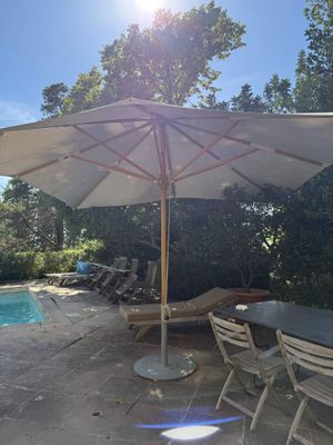 a table and chairs under an umbrella near a pool