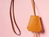 an orange leather purse with a metal hook on a pink background