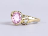 an oval pink sapphire and diamond ring in yellow gold