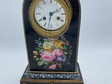 une horloge noire et dorée ornée d'un motif floral