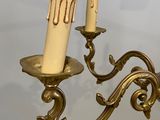 two candles that are hanging from a gold colored chandelier
