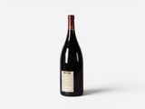 a bottle of red wine sitting on top of a white surface