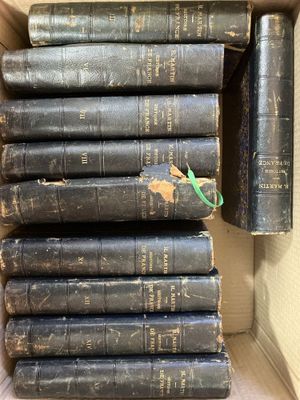 Plusieurs vieux livres sont empilés dans une boîte en carton posée sur une table