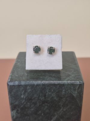 pair of emerald stone stud earrings on display on a marble block