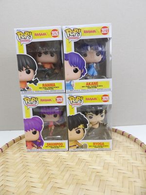 quatre figurines Pop en vinyle représentant des personnages d'anime, disposées dans un panier posé sur une table