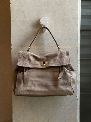 un sac à main en cuir beige accroché au mur devant une porte