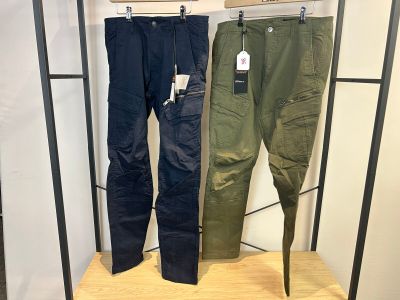 deux pantalons pour homme suspendus à un portant dans un magasin de vêtements
