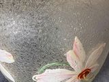 a glass vase with flowers painted on it on a table