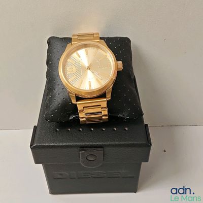 michael korsch gold watch on a black box with a white background