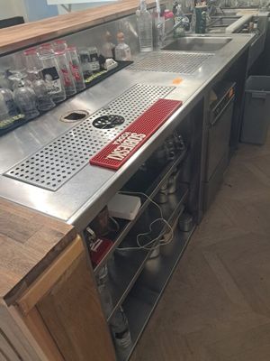 une cuisine avec un évier et un plan de travail sur lequel sont posées de nombreuses bouteilles
