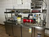 un plan de travail en acier inoxydable dans une cuisine professionnelle, sur lequel se trouvent de nombreux objets