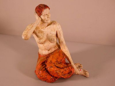 a statue of a man sitting on the ground with his hand on his head