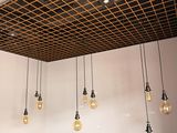 une pièce avec une table, des tabourets et plusieurs lampes suspendues au plafond