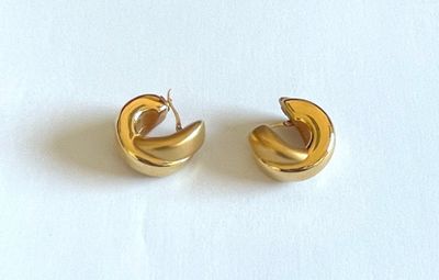 une paire de boucles d'oreilles créoles dorées sur un fond blanc
