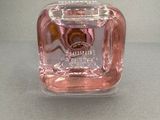 a pink bottle of perfume on a gray surface