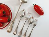 a bowl of tomatoes and spoons next to a bowl of silverware