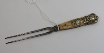une petite fourchette en métal avec un manche, posée sur une surface blanche