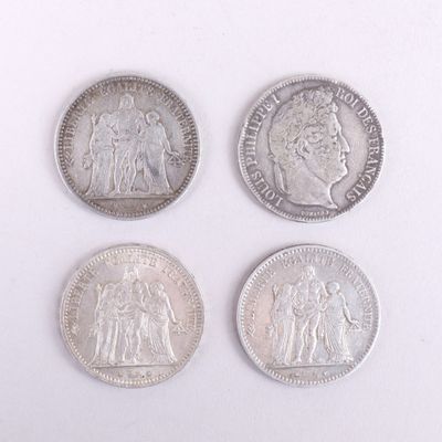quatre types différents de pièces d'argent sur une surface blanche