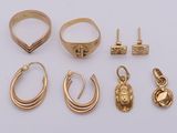 several gold rings and earrings on a white surface