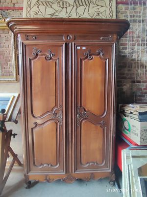 a wooden armoire in a room with a painting on the wall
