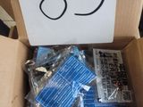 une boîte en carton remplie d'objets divers et une pancarte sur laquelle est inscrit « 85 »