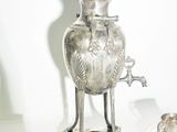 un vase en argent posé sur une table, à côté d'autres plats en argent