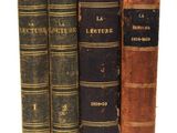 trois vieux livres posés l'un sur l'autre sur une surface blanche
