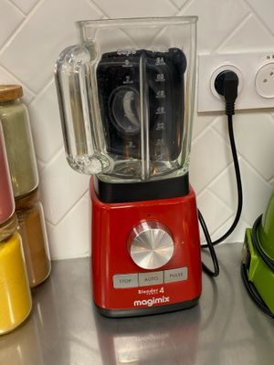 a red blender sitting on a kitchen counter next to a green blender