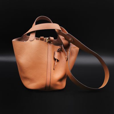 a tan leather bucket bag on a black background