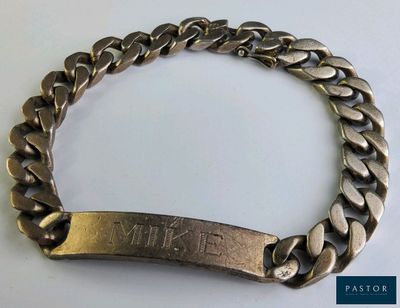 un gros plan sur un bracelet en métal sur lequel figure un nom