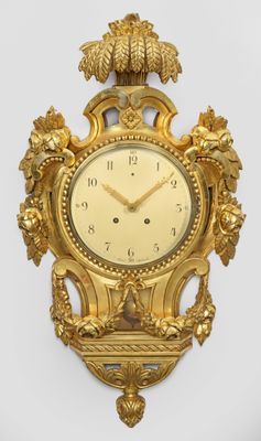 une horloge en or accrochée au mur, sur laquelle est représenté un oiseau