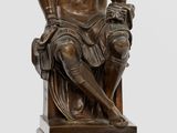a bronze statue of a man sitting on a bench