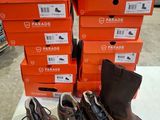 quatre paires de chaussures sont alignées sur une table devant des cartons orange