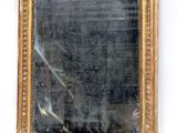 an image of a gold framed mirror sitting on top of a white wall