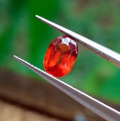 a red stone that is being held by a pair of pliers