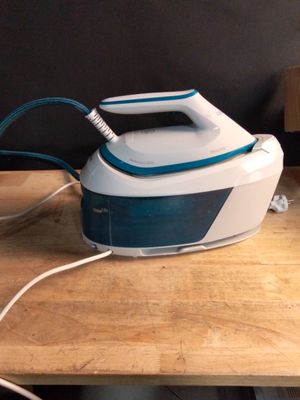 un fer à repasser à vapeur blanc et bleu posé sur une table en bois