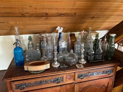 de nombreux vases en verre posés sur une commode dans une pièce