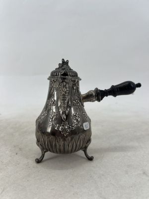 une théière ancienne en argent avec une poignée noire sur une surface blanche